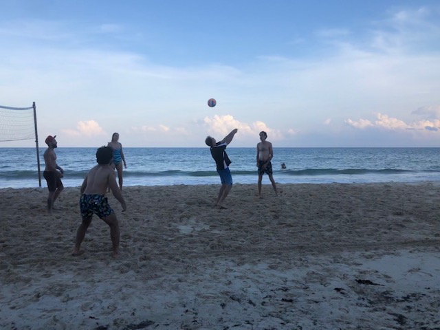 People playin gbeach volleyball in the evening.